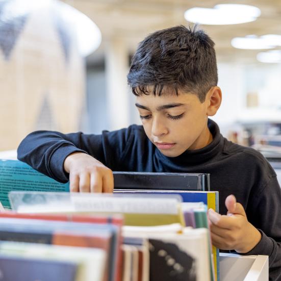 Dreng bladrer i bøger.