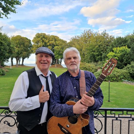 Rene Richardt og John Kofoed foran en græsplæne og træer i horisonten.