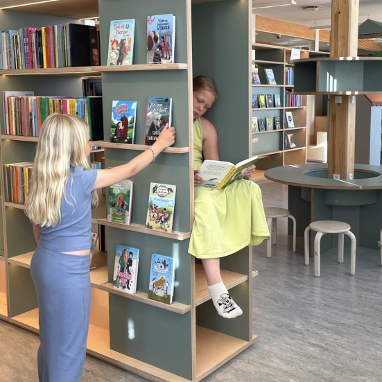 To piger der vælger bøger på Helsinge Bibliotek