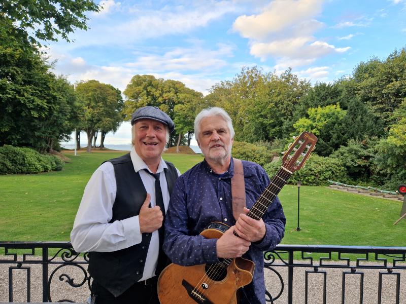 Rene Richardt og John Kofoed foran en græsplæne og træer i horisonten.