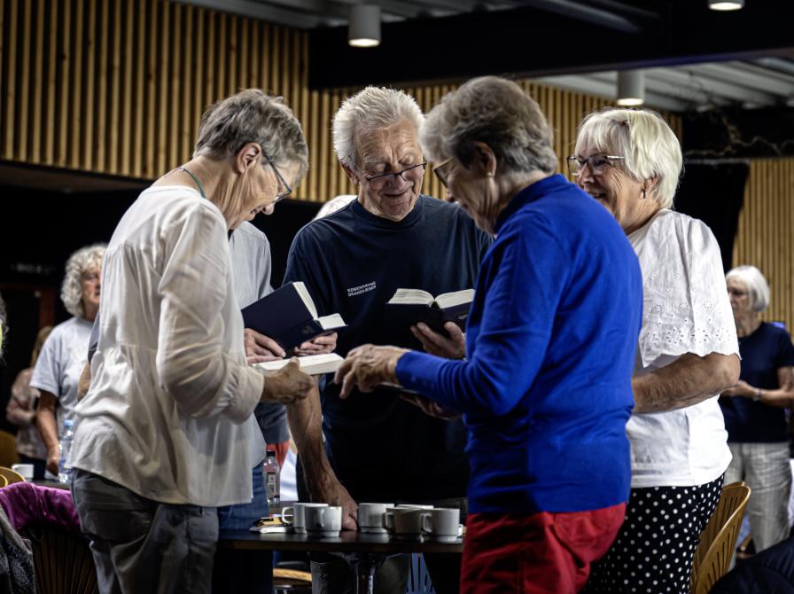 Fire deltagere synger fra Højskolesangbogen.