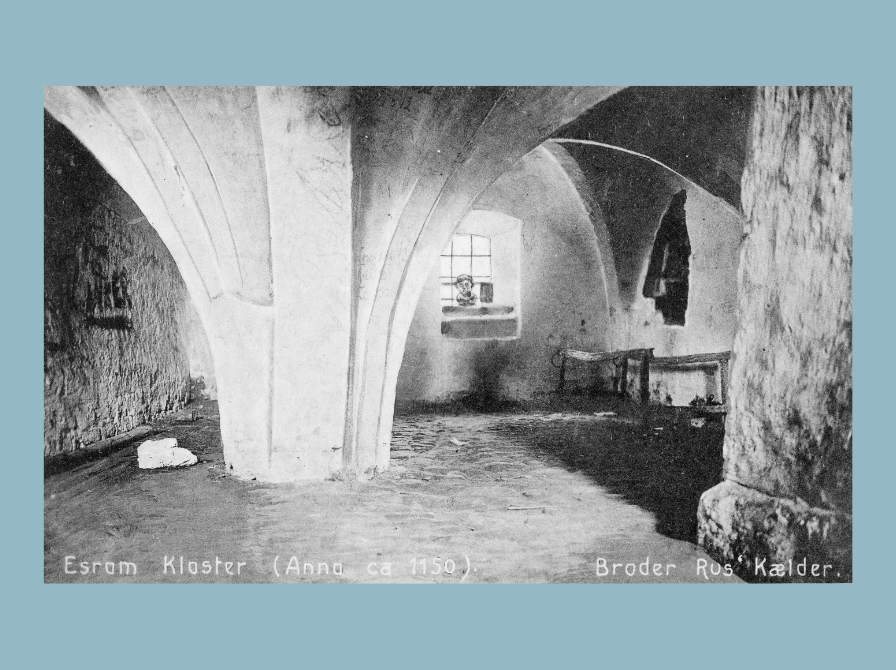 Sort-hvidt fotografi af en gammel kælder med hvælvet loft og brosten på gulvet.